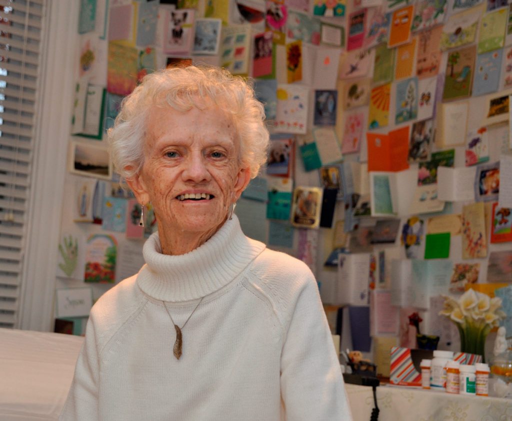 Sister Pat relaxes by her “wall of love” while wearing a special feather necklace. “This feather reminds me of what it is that I strive for, to be a feather on the breath of God,” she says. Photo by Catherine Walsh/Northeast Communications.