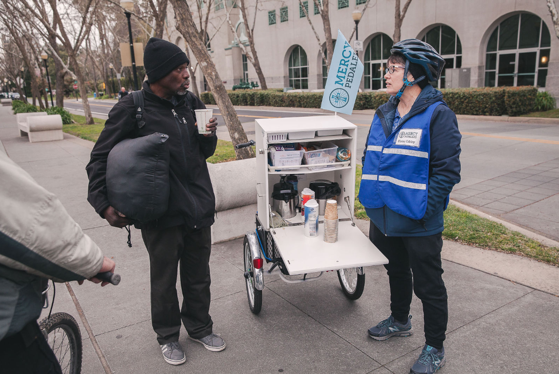 Sister Libby speaking with a man she met while pedaling her route. Photo via Create + Gather