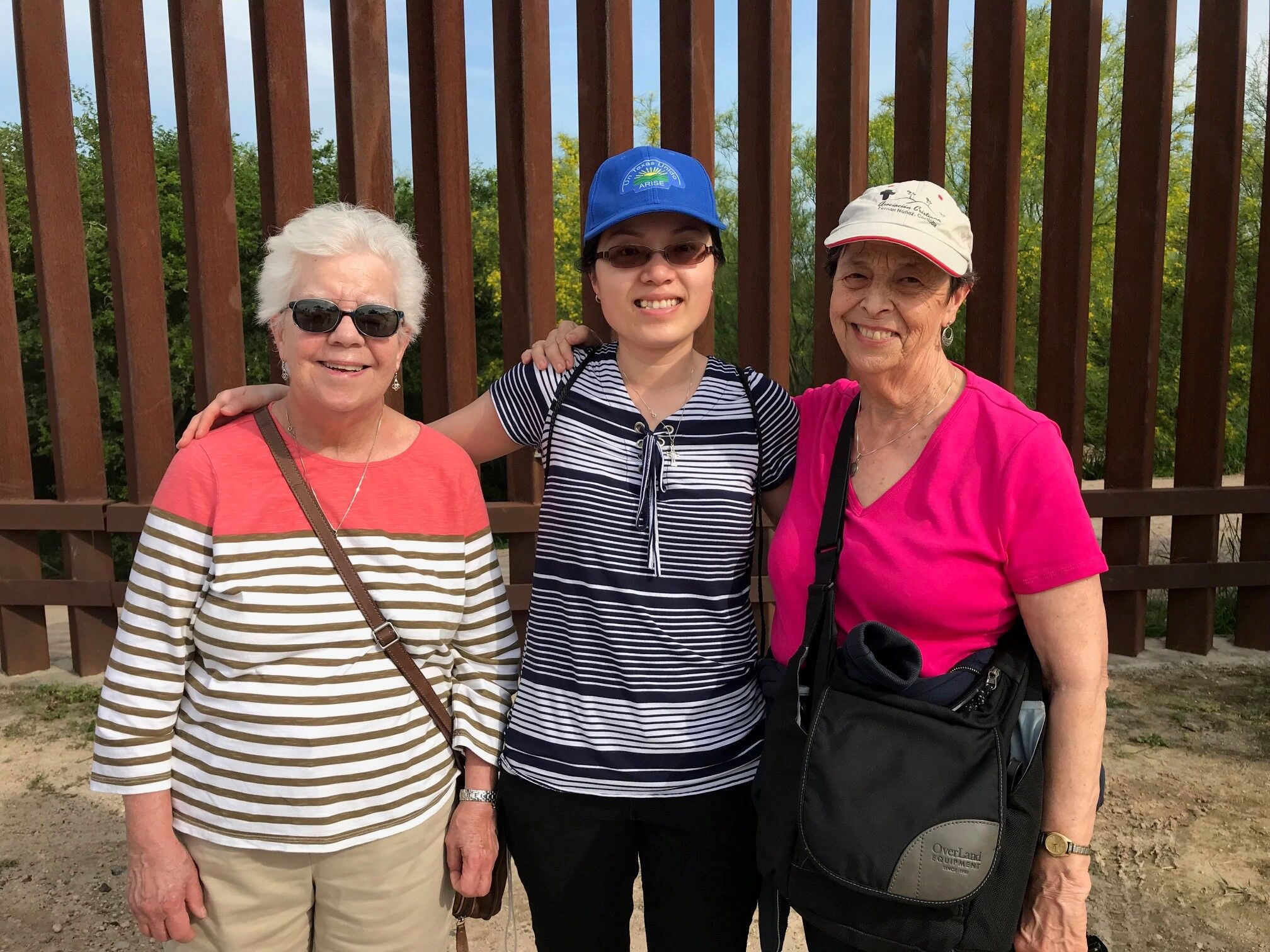 Hermanas Joanne Whitaker, Phuong Dong y Marilyn Morgan de pie junto a la valla de la frontera en Hidalgo, Texas.