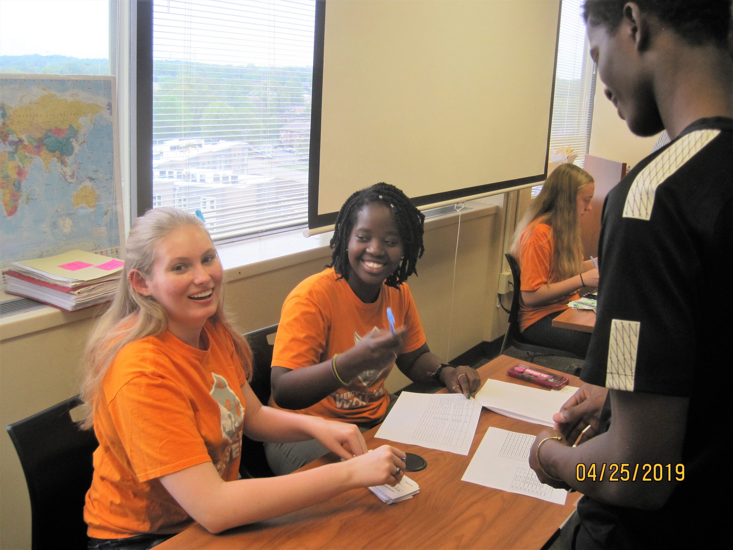 Two Mercy McAuley students sharing a laugh with a young man who recently was resettled to the Cincinnati area.