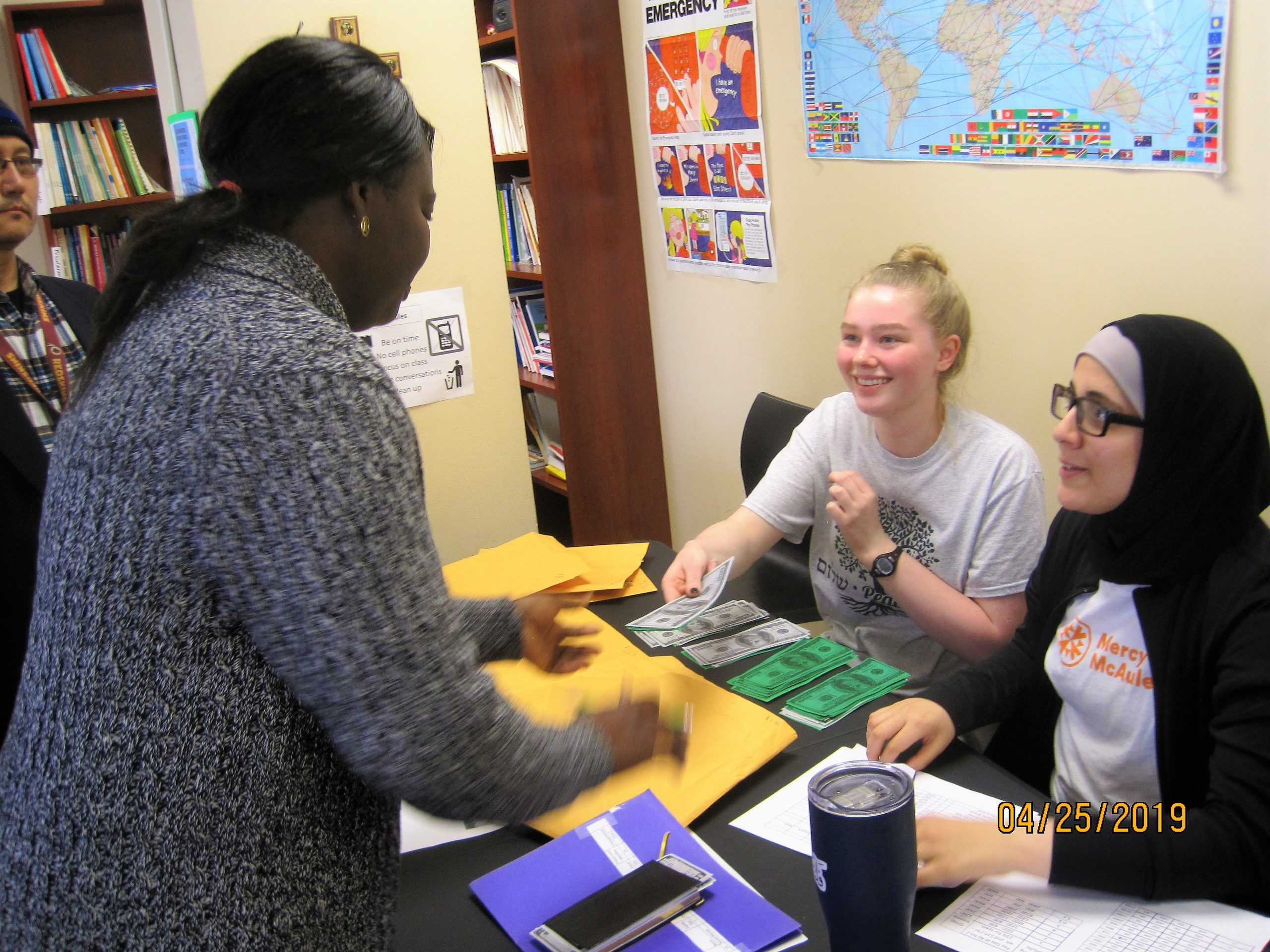 Mercy McAuley students helping a woman learn the basics about how different financial transactions work in the United States.