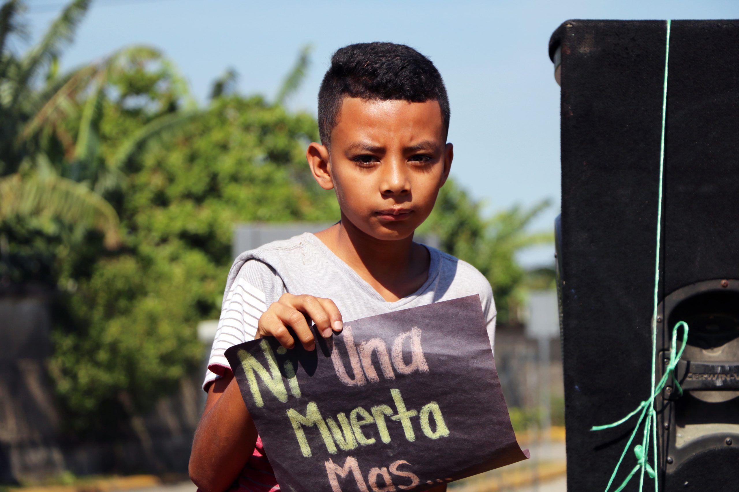 A young boy holds up a sign that says “not one more woman killed.”