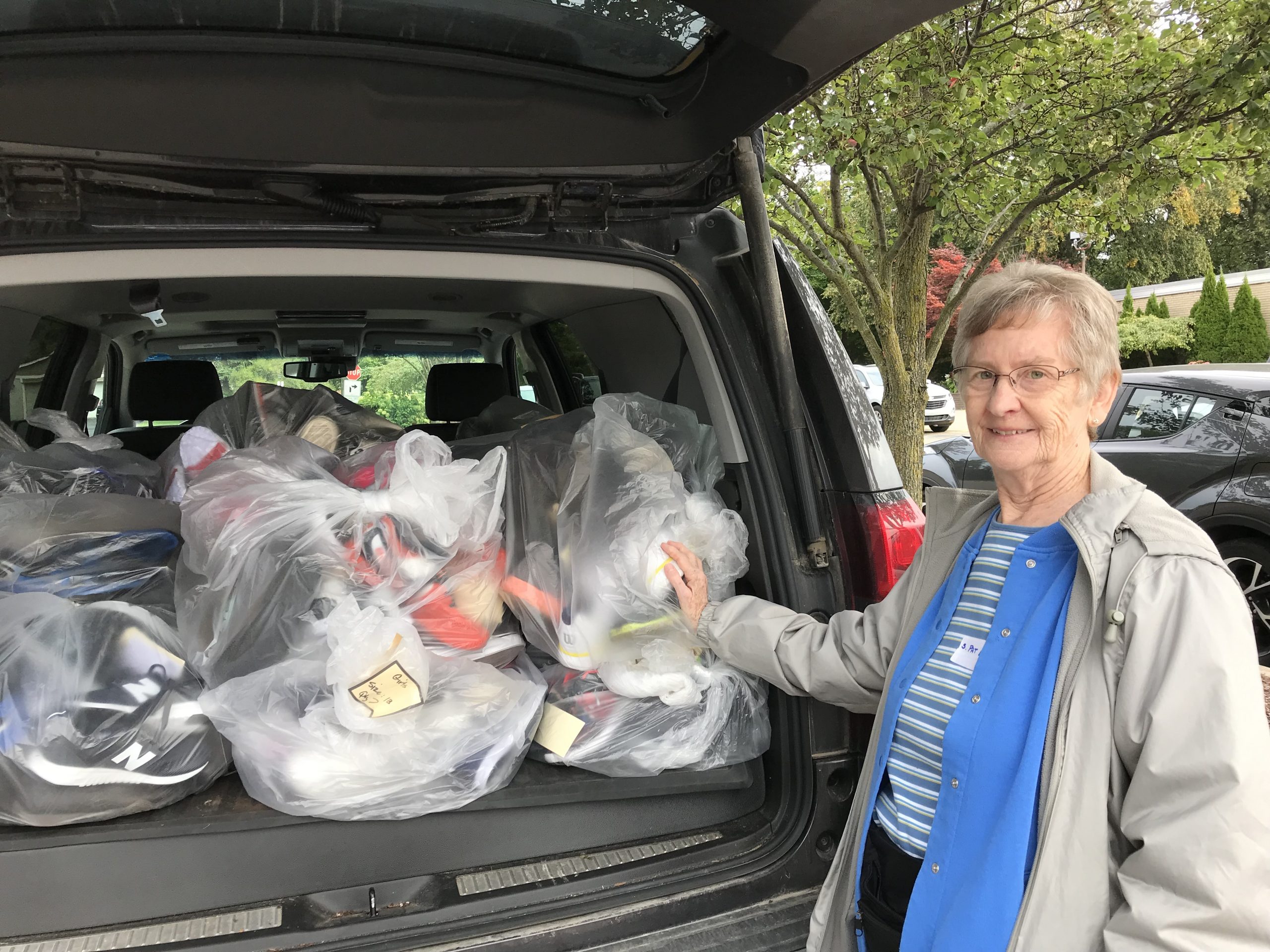 A picture of Sister Pat lamb with donated shoes and supplies for immigrants who are students at local schools.