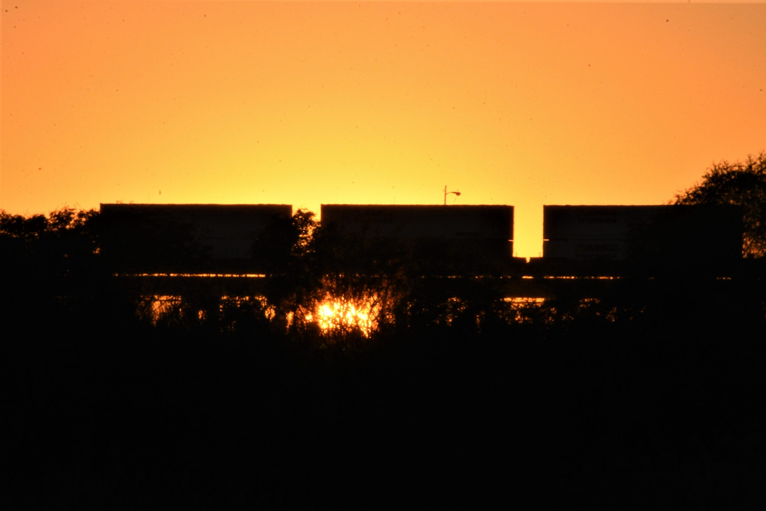 Un tren de carga en la tarde, durante la puesta del sol, viaja de México a Laredo.
