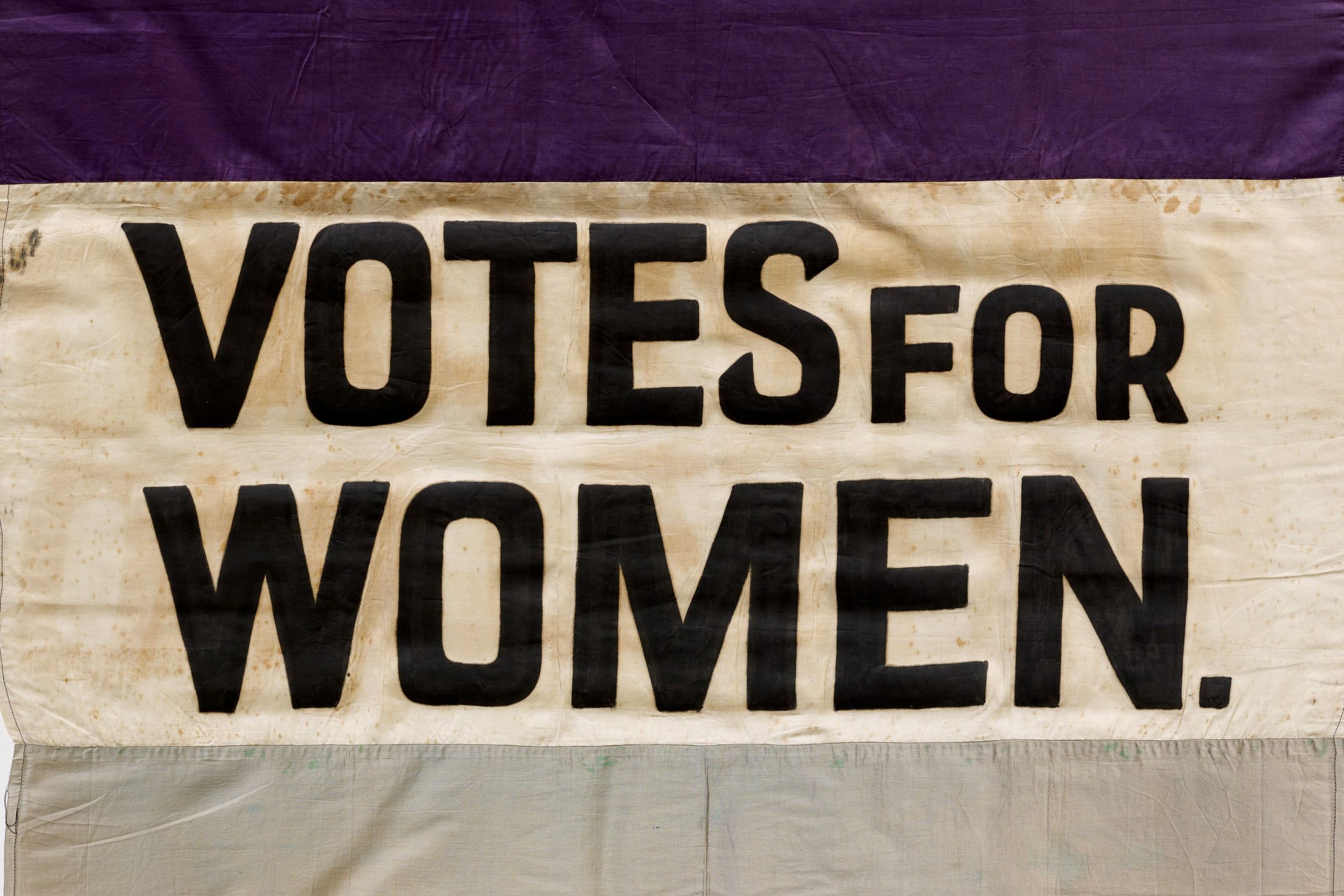An image of an old banner about women voting.
