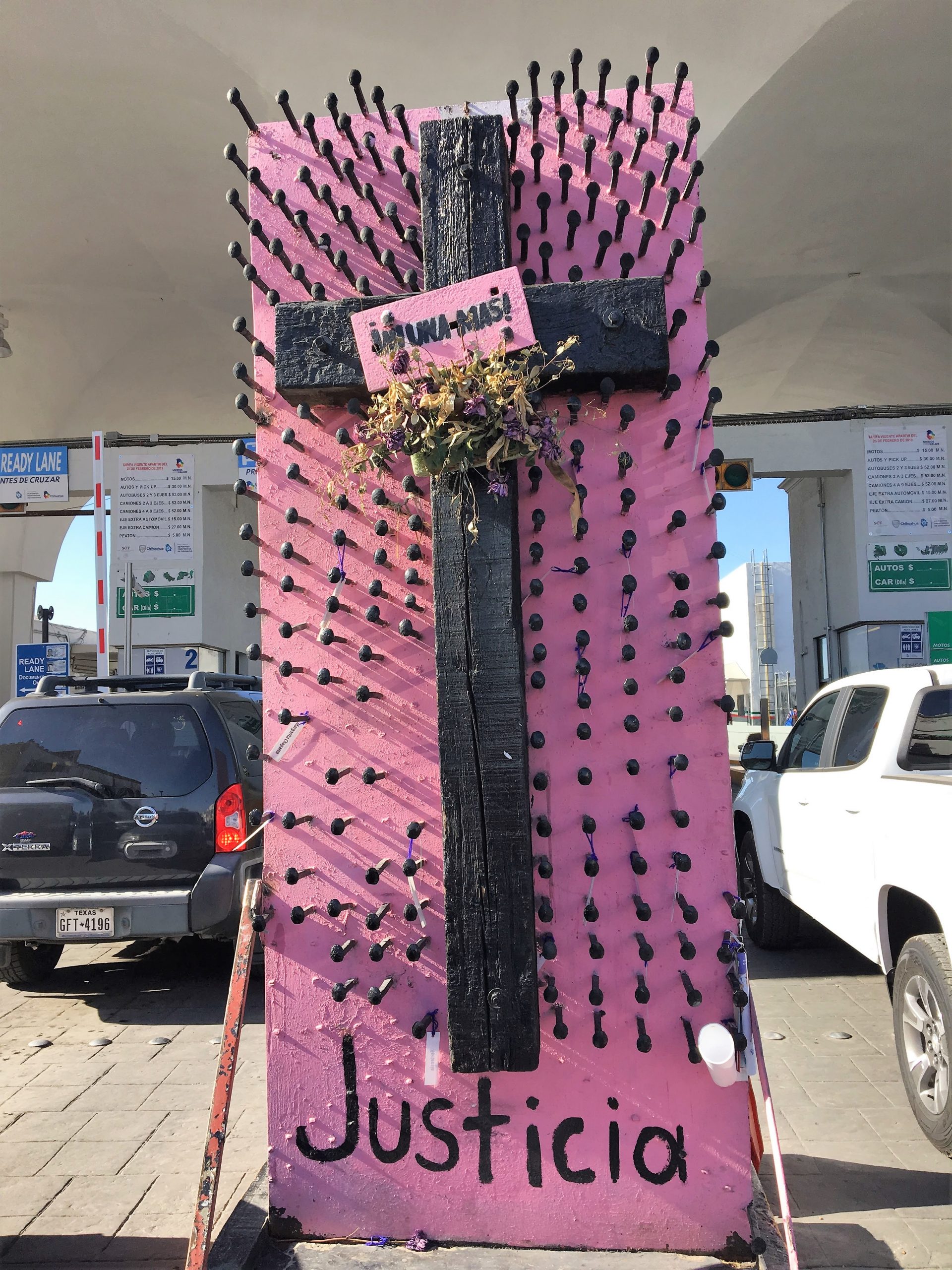 A cross by a checkpoint on the Juárez side of the Paso del Norte Bridge into El Paso. The names of deceased migrants hang from the nails.